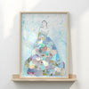 Framed artwork of a woman in a dress made from various collage pieces on a white wall.