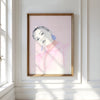 Framed artwork of a woman's portrait on a wall with sunlight streaming in